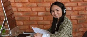 Mujer joven de soporte técnico con auriculares frente a un computador